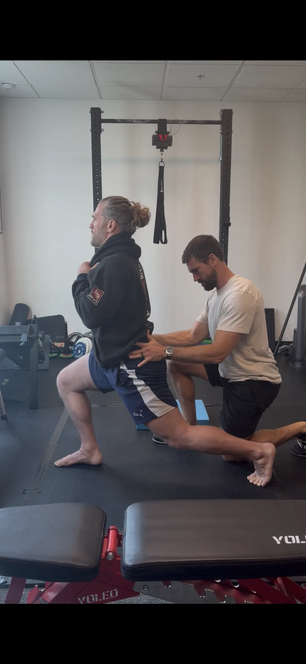 Dr. Garret George performing a hands-on hip and low back exam during a loaded split squat at GG Chiropractic in Irvine